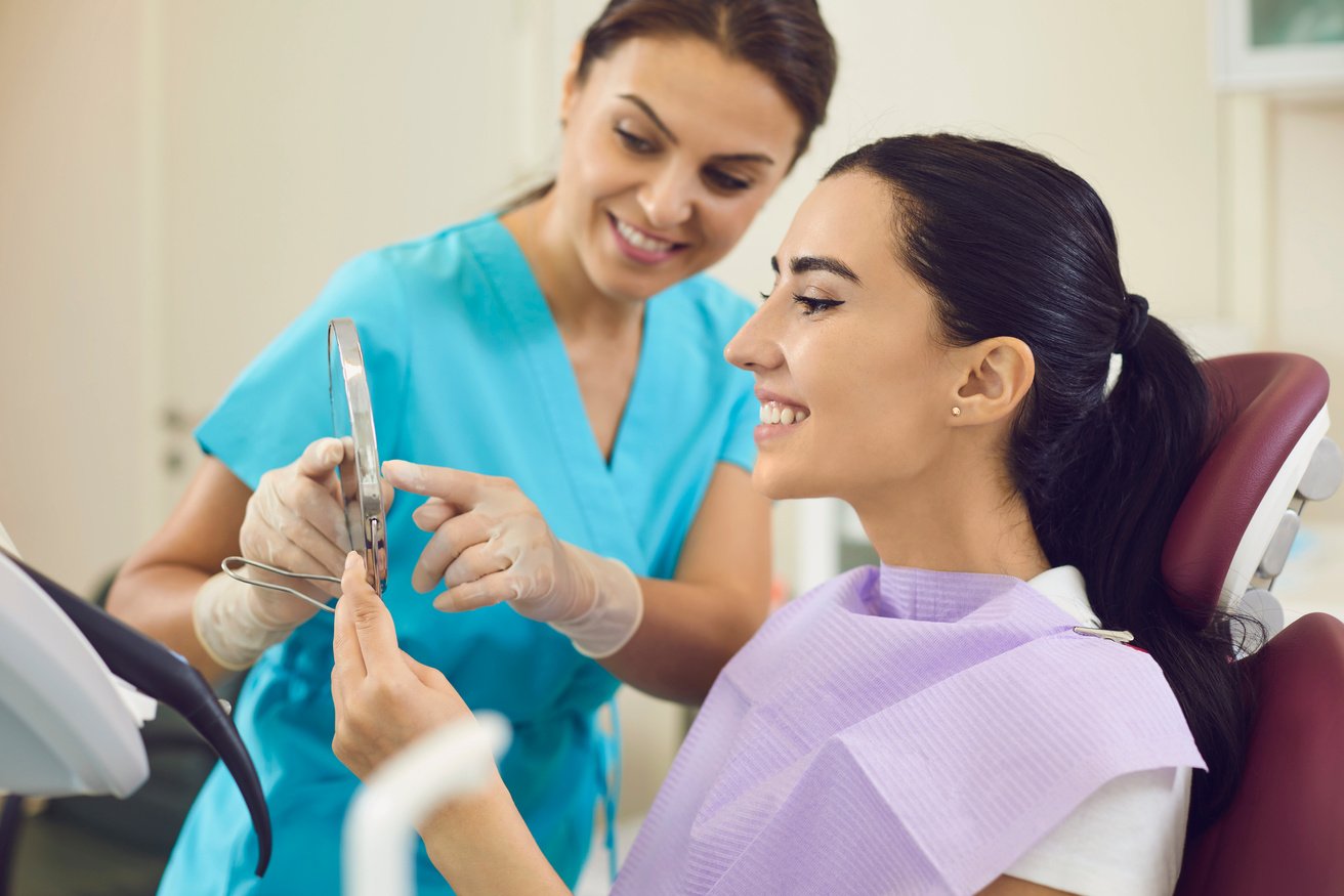 Happy Woman in Dental Chair Looking at the Result of Professional Teeth Cleaning and Whitening