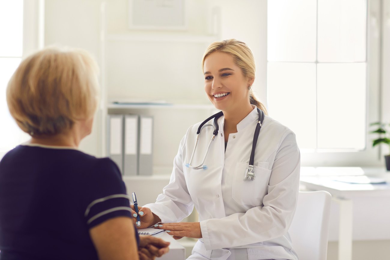 Woman Doctor Sitting and Making Notes during Consultation with Mature Woman Patient